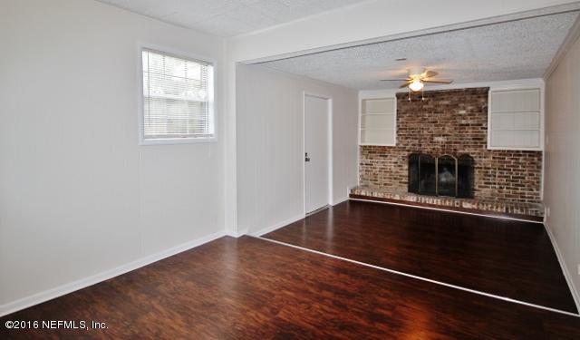6328 Merrill Road Jacksonville, FL 32277 - Photo 3 of 10 an empty room with wooden floor fireplace and windows