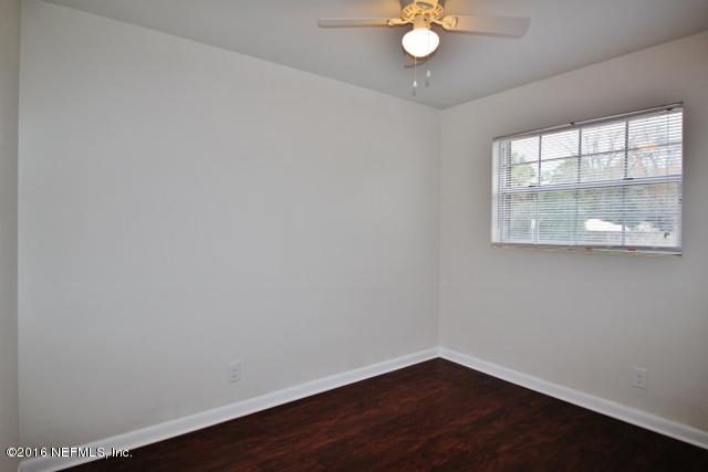 6328 Merrill Road Jacksonville, FL 32277 - Photo 7 of 10 an empty room with wooden floor and windows