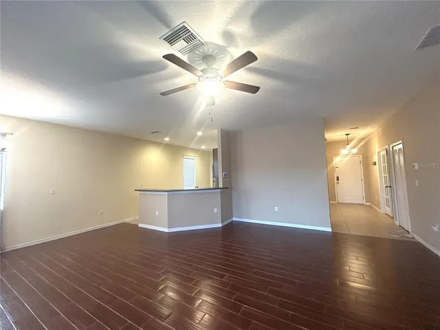 a view of an empty room with window and wooden floor