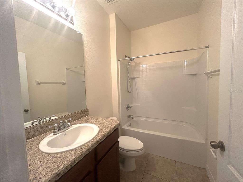 10702 Burning Bush Terrace Land O Lakes, FL 34638 - Photo 21 of 22 a bathroom with a granite countertop sink toilet mirror and shower