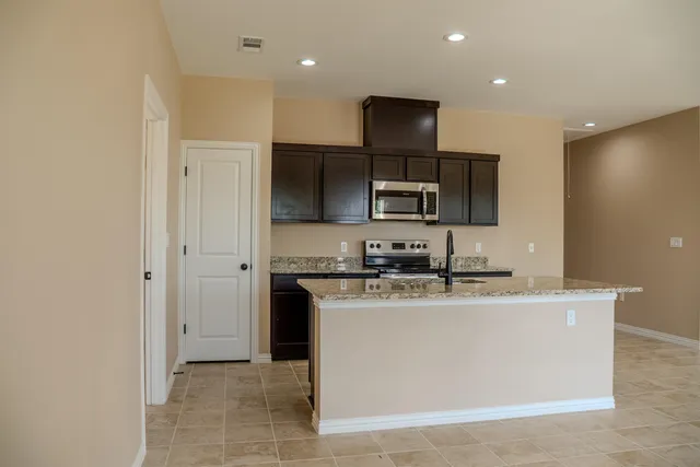 a kitchen with kitchen island granite countertop a sink and steel appliances
