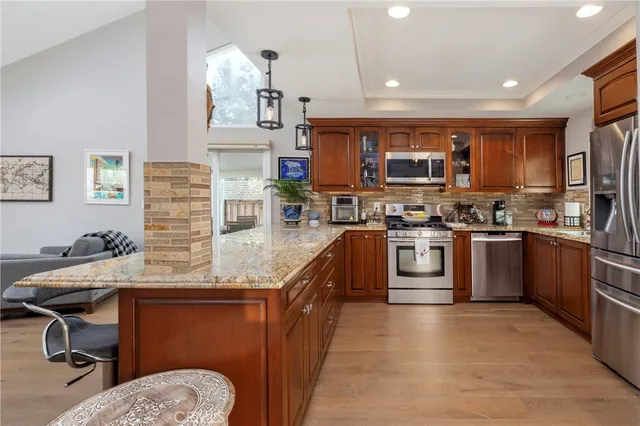 a kitchen with stainless steel appliances granite countertop a stove top oven a sink and a refrigerator