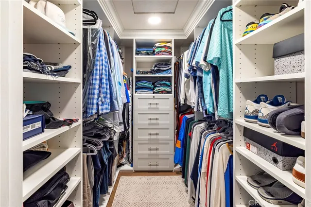 a view of walk in closet with clothes and shoes