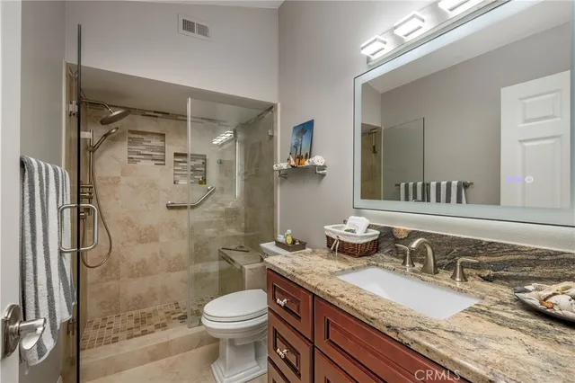 a bathroom with a granite countertop sink toilet and shower