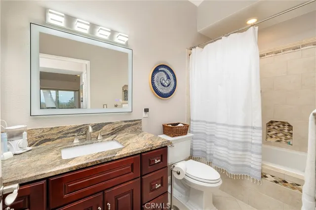 a bathroom with a granite countertop toilet sink and mirror