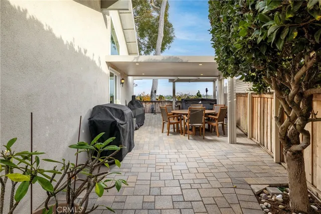 a view of a patio with table and chairs potted plants and a large tree
