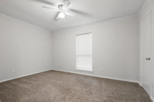 an empty room with a window and ceiling fan