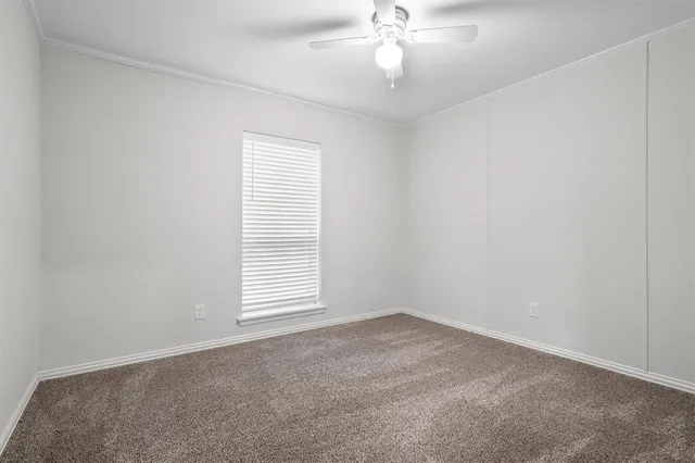 an empty room with a window and ceiling fan