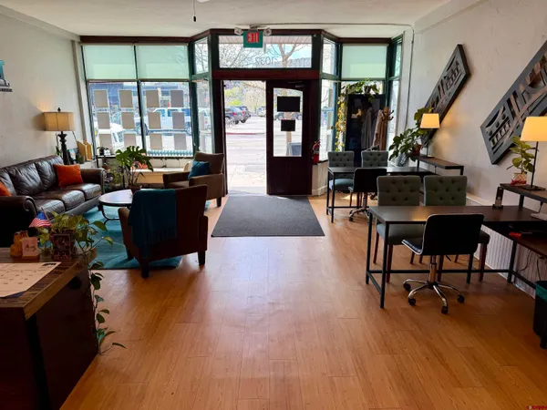 a living room with furniture a floor to ceiling window and wooden floor