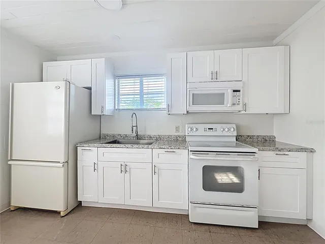 a kitchen with cabinets appliances a sink and a window