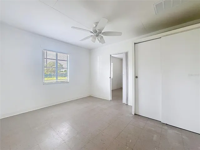 an empty room with windows and fan
