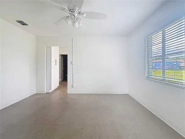 an empty room with windows and fan