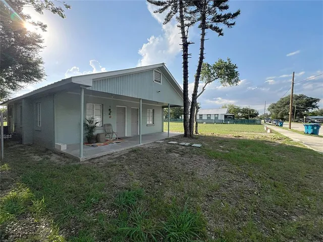 a view of a house with backyard and a tree