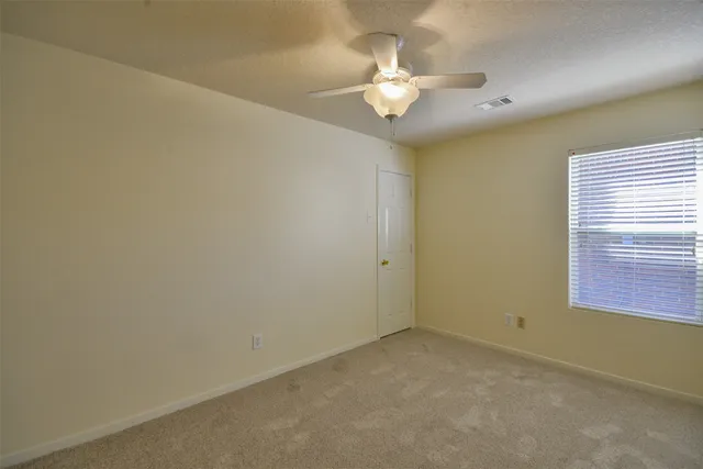 an empty room with a chandelier fan and window