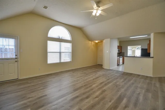 a view of empty room with wooden floor and fan