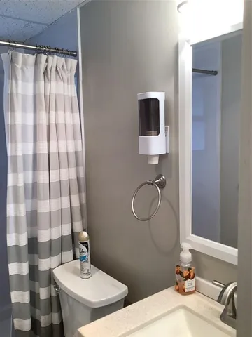a bathroom with a sink toilet a mirror and shower curtain