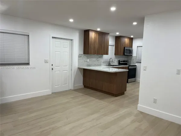 a view of kitchen with kitchen island wooden floor center island and stainless steel appliances