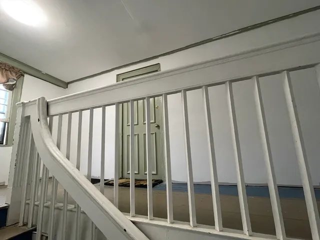 a view of staircase with railing and white walls