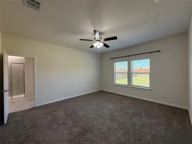 an empty room with windows and ceiling fan