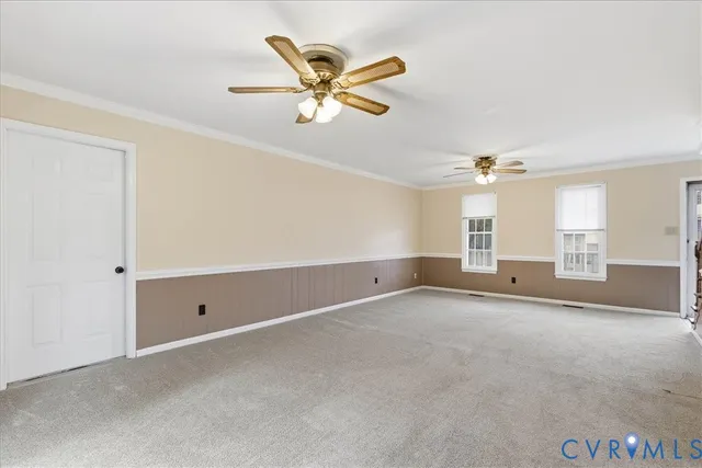 an empty room with chandelier fan and windows