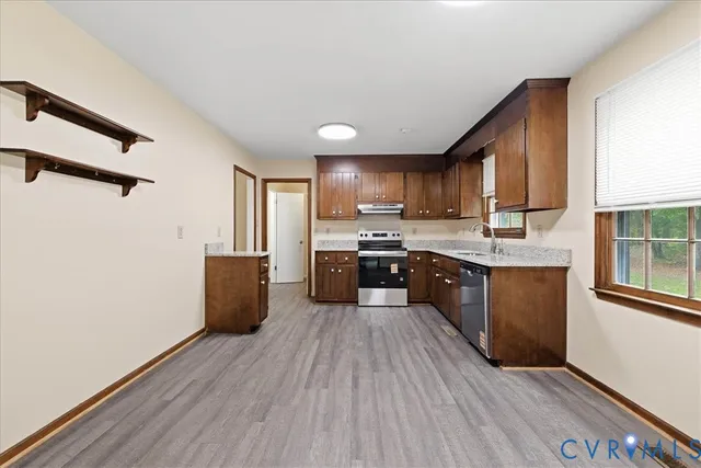 a large kitchen with stainless steel appliances granite countertop a stove a sink dishwasher and a refrigerator with wooden floor