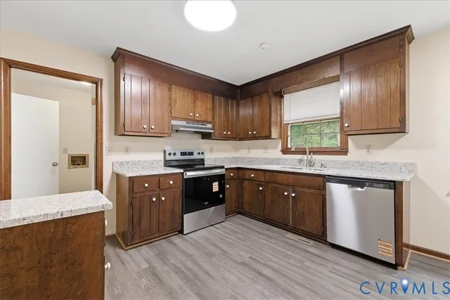 a kitchen with stainless steel appliances granite countertop wooden cabinets a stove top oven a sink and dishwasher