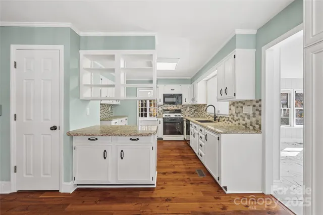 a kitchen with granite countertop a stove a sink and a refrigerator