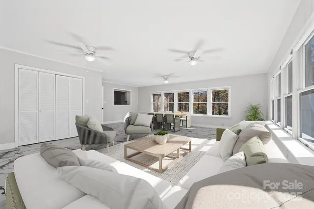 an empty room with chandelier fan and windows