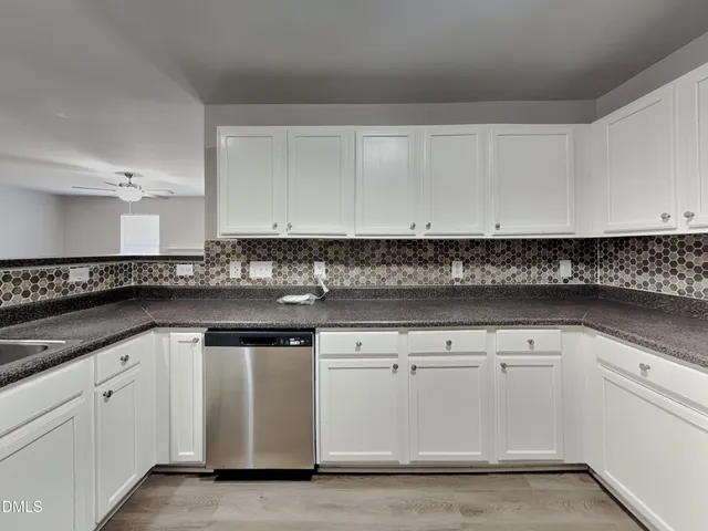 a kitchen with granite countertop white cabinets and a sink