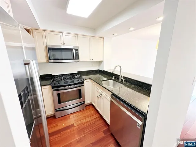 a kitchen with granite countertop white cabinets and stainless steel appliances