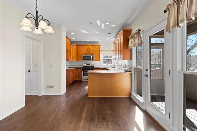 a kitchen with stainless steel appliances granite countertop wooden cabinets a stove a sink and a microwave