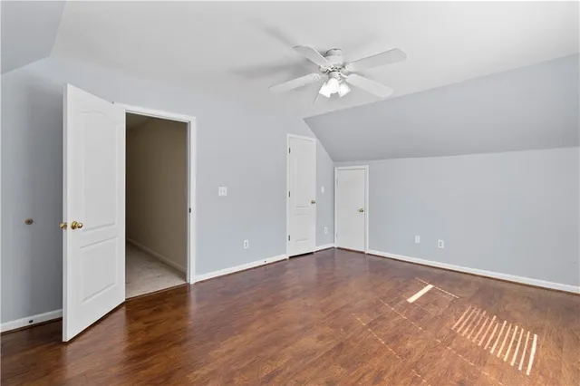 an empty room with a chandelier fan and wooden floor