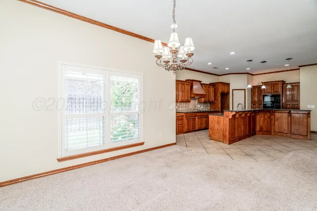 an empty room with chandelier fan and windows