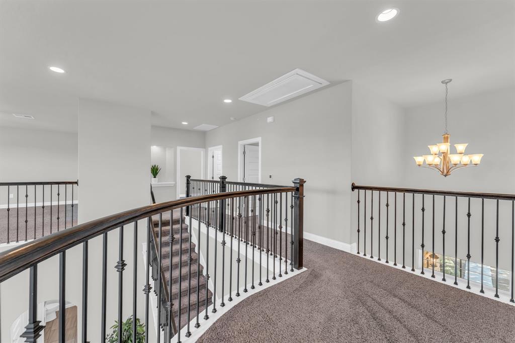 110 Magona Trail Georgetown, TX 78628 - Photo 28 of 38 A graceful staircase with intricate iron balusters leads to an open, carpeted landing featuring recessed lighting.