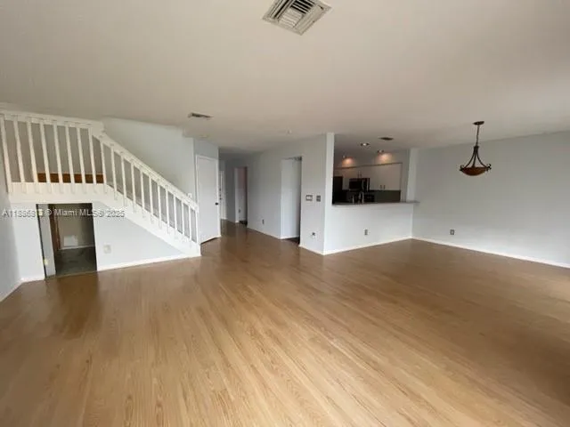 a view of a livingroom with wooden floor and staircase