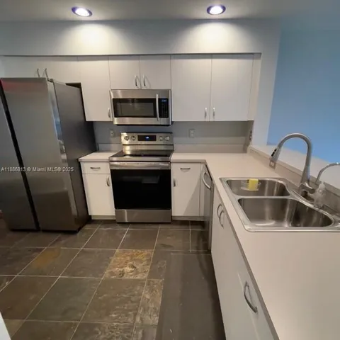 a kitchen with kitchen island a sink stainless steel appliances and cabinets