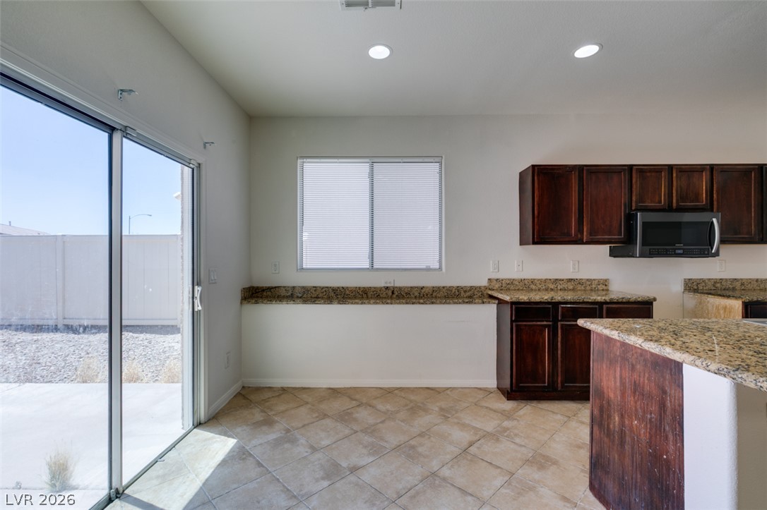 5150 Riverside Run Court North Las Vegas, NV 89081 - Photo 24 of 50 A well-lit kitchen with granite countertops and rich wood cabinetry, offering direct access to the outdoors.