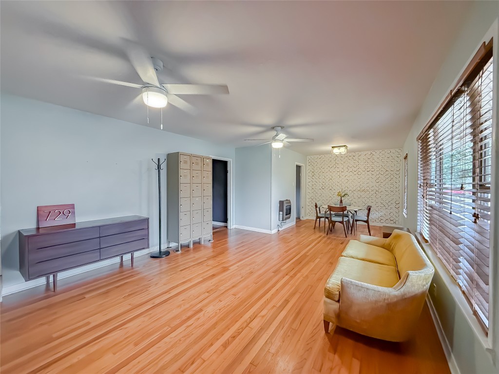 729 Main Street Lexington, TX 78947 - Photo 3 of 15 Living area featuring an accent wall, light wood-style flooring, wallpapered walls, heating unit, and ceiling fan