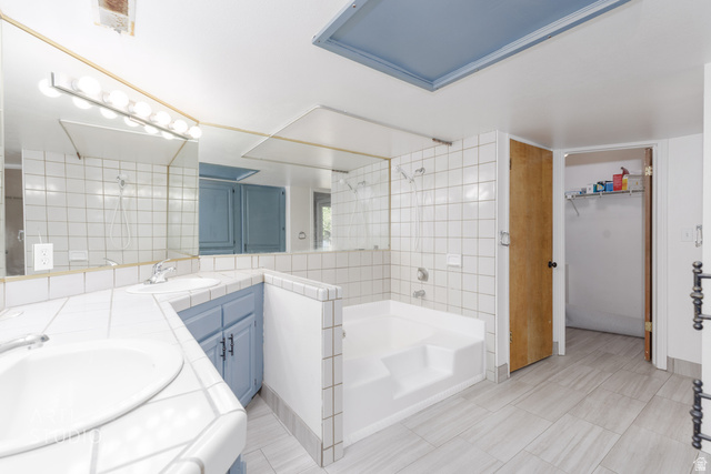 860 South Village Road, Unit A6 St. George, UT 84770 - Photo 11 of 41 Full bathroom featuring double vanity, a walk in closet, a shower, a garden tub, and tile walls