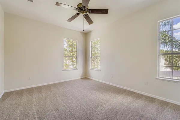an empty room with windows and fan