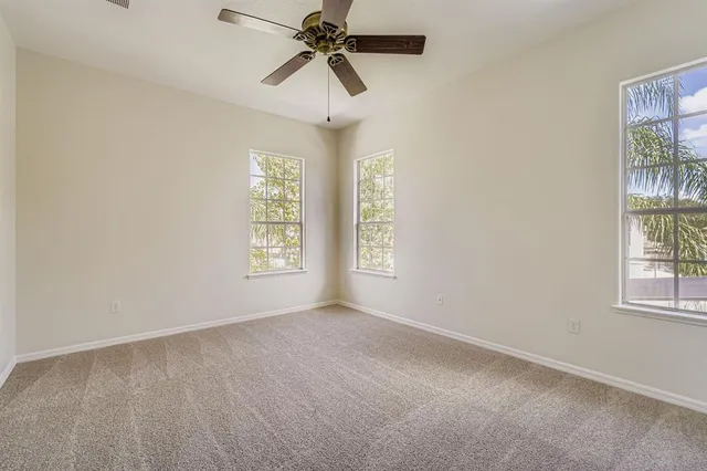 an empty room with windows and fan