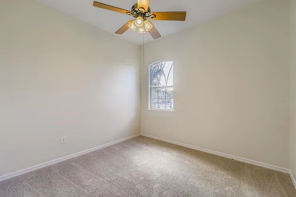 an empty room with a window and a fan