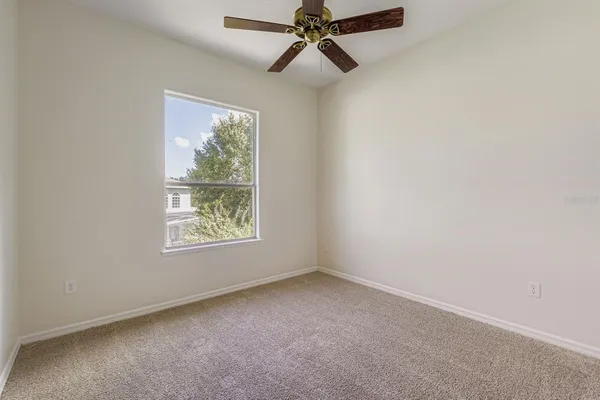 an empty room with a window and a ceiling fan