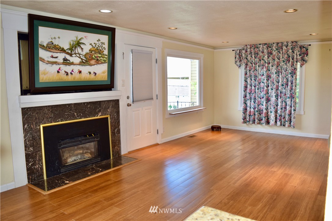 357 Lind Avenue Northwest Renton, WA 98057 - Photo 8 of 27 an empty room with windows a fireplace and wooden floor