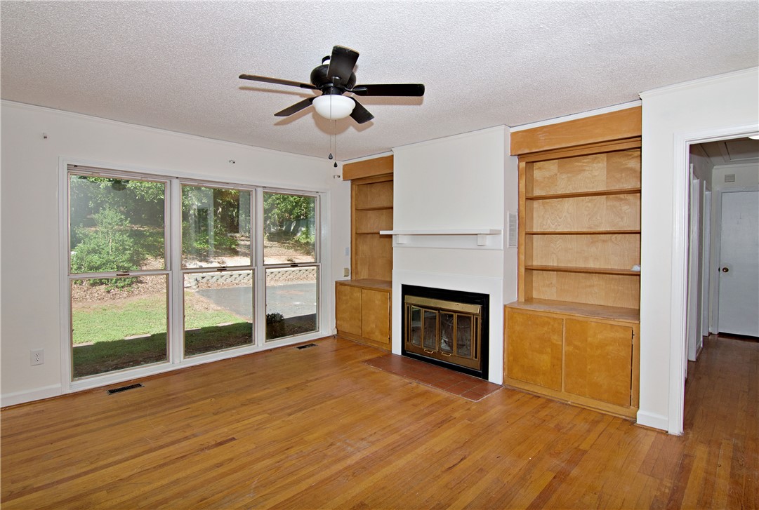 102 Broad Street Clemson, SC 29631 - Photo 13 of 40 Hardwood floors and a cozy fireplace anchor this living area, complemented by large windows overlooking the natural landscape.