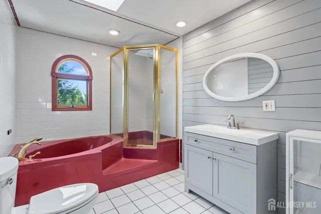 a bathroom with a toilet sink vanity tub and mirror