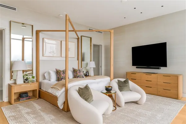 a bedroom with a bed television and a large window