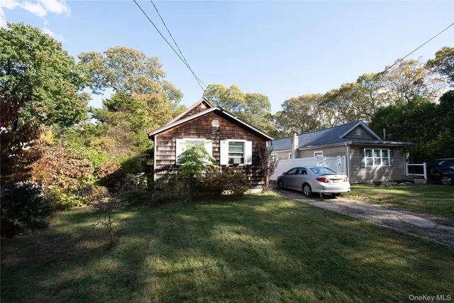 a view of a house with a big yard and large trees