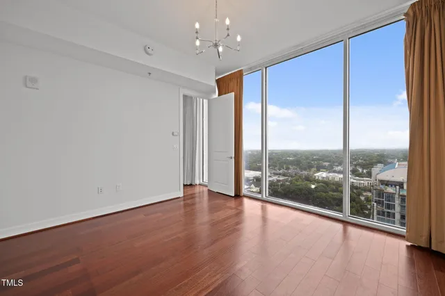 a view of an empty room with wooden floor and windows