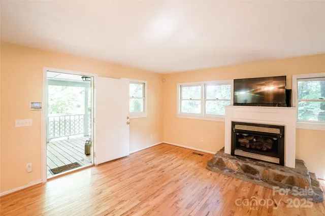 an empty room with windows a fireplace and wooden floor